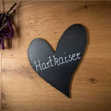 A heart-shaped slate sign with the inscription "Hutkaiser". The background is made of light wood.