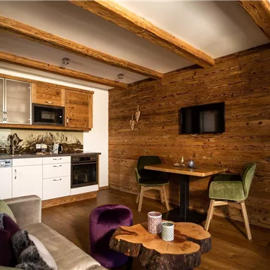 A cozy living space with wooden ceilings and modern furniture. The kitchen is well-equipped, and a small dining table invites you to linger.