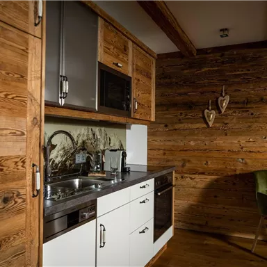 A cozy kitchen with modern appliances and wood paneling. The room has a warm, inviting ambiance.