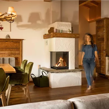 A cozy living room with a modern fireplace and wooden furniture. A person moves about the room in a relaxed manner.