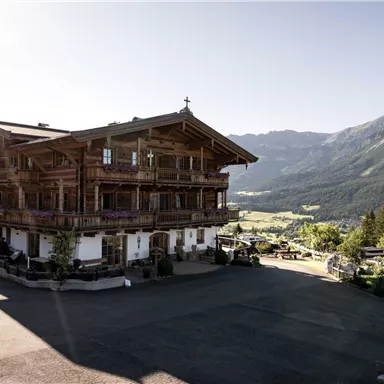 A traditional wooden house in the mountains, surrounded by green forests and majestic peaks. The clear air and the peaceful surroundings create an inviting atmosphere.