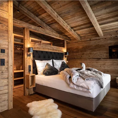A cozy bedroom with wooden walls and a large bed. The room is modernly furnished and radiates warmth.