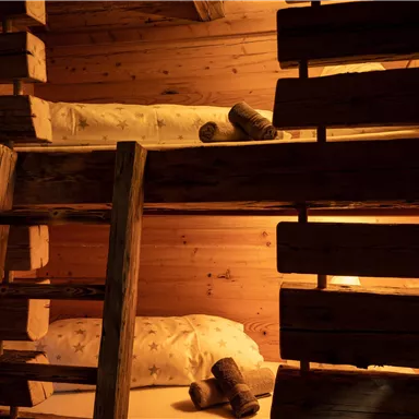 A cozy bedroom with wooden bunk beds. The warm lights create an inviting atmosphere.