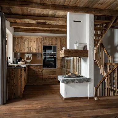 A cozy wooden house with an open kitchen and staircase. The space is bright and modernly designed, with warm wood tones.