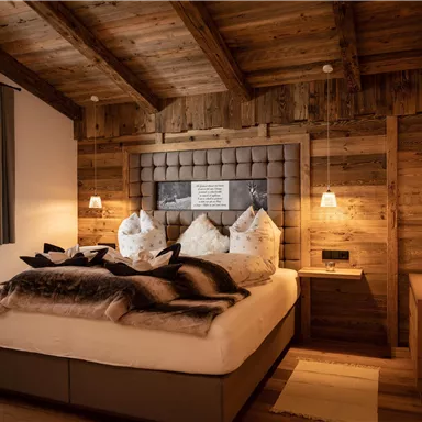 A cozy bedroom with wood details and a large bed. Soft lighting and a rustic atmosphere create a relaxing environment.