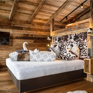 A cozy bedroom with wooden walls and a large bed. The rustic decor creates an inviting atmosphere.