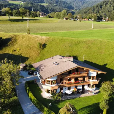 Ein schönes Haus in ländlicher Umgebung, umgeben von saftigem Grün und Bergen. Die ruhige Landschaft lädt zur Entspannung ein.