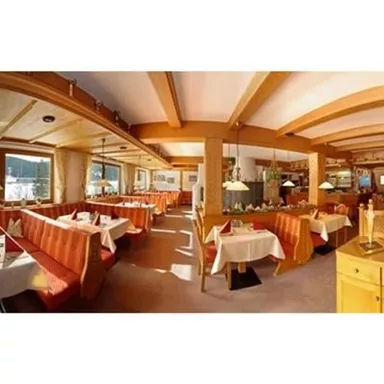 A cozy restaurant with wooden elements and warm colors. The tables are carefully set, and there is plenty of natural light.