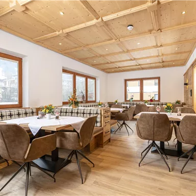 Ein gemütliches Restaurant mit Holzverkleidung und modernen Möbeln. Die Tische sind mit Blumen dekoriert und bieten eine einladende Atmosphäre.