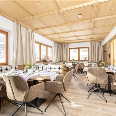 Ein modernes Restaurant mit Holzdecken und gemütlichen Sitzplätzen. Große Fenster bieten einen Blick auf die Umgebung und sorgen für viel natürliches Licht.