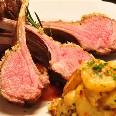 Tender lamb chops on a plate, perfectly grilled and lightly pink. Served with a side salad and spicy potatoes.
