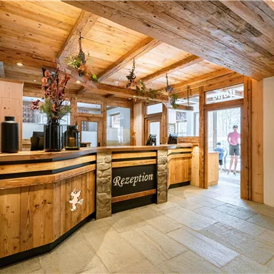 Ein gemütlicher Empfangsbereich mit Holzdekor und einer einladenden Theke. Der Raum hat viel natürliches Licht und eine freundliche Atmosphäre.
