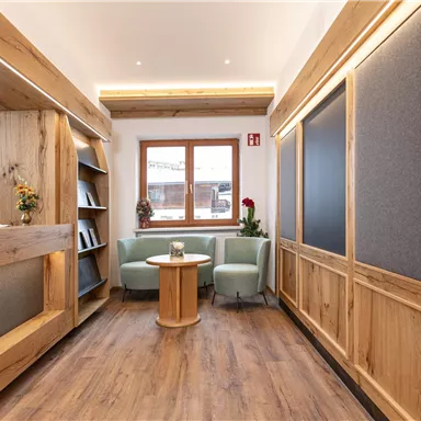 Ein gemütlicher Raum mit Holzverkleidung. Es gibt eine kleine Sitzecke mit einem Tisch und Pflanzen sowie Bücherregale an der Wand.