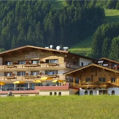 Ein charmantes Hotel in den Bergen mit Holzfassade und Balkonen. Umgeben von grünen Wäldern und einer schönen Landschaft.