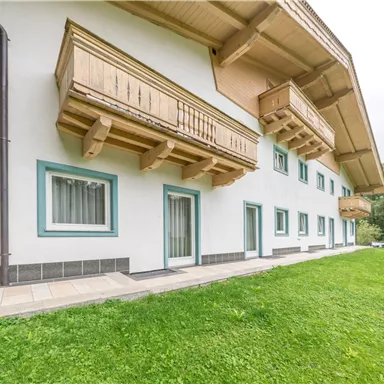 A modern building with wooden cladding and balconies. The lawn is well-maintained and the sky is overcast.