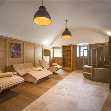 A relaxing wellness area with wooden loungers and warm light. The atmosphere is calm and welcoming.