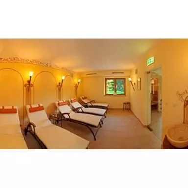 A relaxing wellness area with loungers and soft lighting. The walls are painted in warm tones, creating a calming atmosphere.