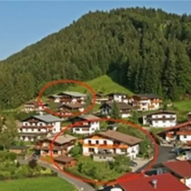 Eine malerische Berglandschaft mit traditionellen Häusern und grünen Wiesen. Die Umgebung ist von dichten Wäldern umgeben und bietet eine ruhige Atmosphäre.