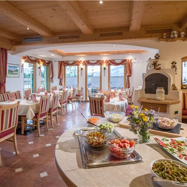 Ein gemütliches Restaurant mit Holzdekor und Tischen, die mit gestreiften Stoffen eingedeckt sind. Auf einem Tisch sind verschiedene Salate und frische Zutaten angerichtet.
