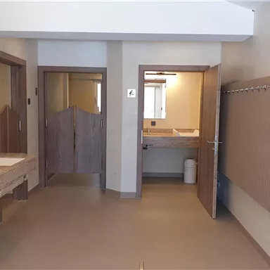 A modern bathroom with several sinks and large mirrors. There are bright walls and separate doors to other rooms.