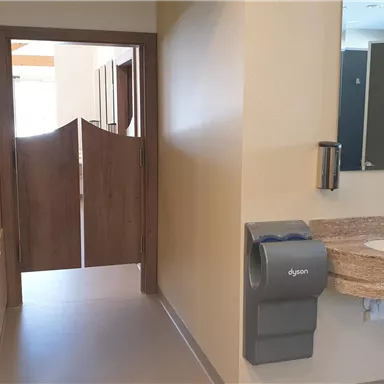 A modern designed sanitary area with a hand washing station and access to restrooms. The walls are kept in neutral colors, creating a pleasant atmosphere.