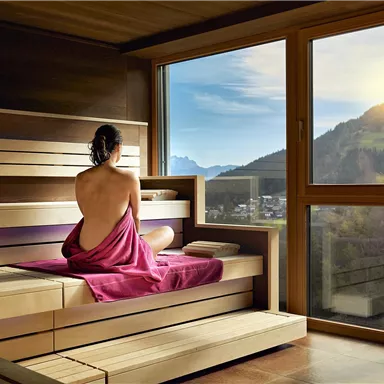 A relaxing sauna with a view of the mountains. One person is sitting in a towel and enjoying the scenery.