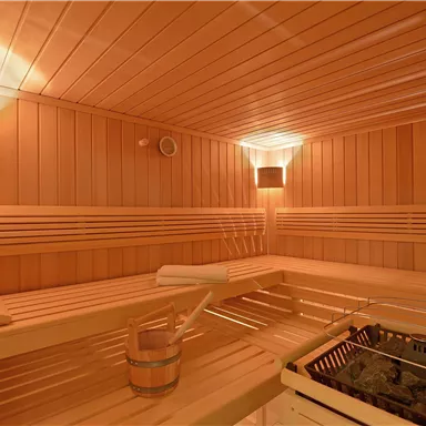 A stylish sauna with wooden paneling and soft lighting. The benches provide plenty of space to relax.