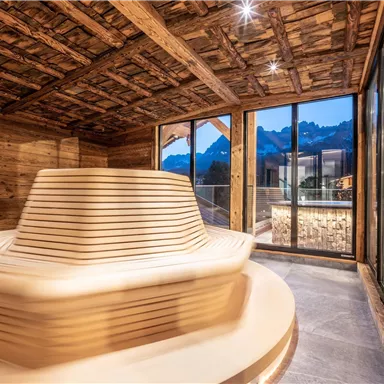 A modern spa with a stylish hot tub and large windows. The wooden walls and the view of the mountains create a relaxing atmosphere.