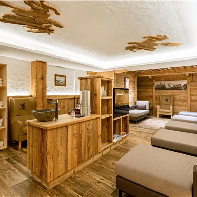 Ein gemütlicher Wellnessbereich mit Holzmöbeln und bequemen Liegen. Sanfte Beleuchtung schafft eine entspannte Atmosphäre.