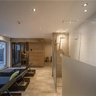 A modern bathroom with a shower and stylish furniture. Large windows let in plenty of natural light.