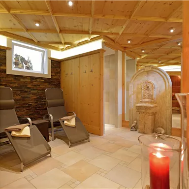 A relaxing wellness area with modern loungers and a warm wood finish. Red candles create a cozy atmosphere.