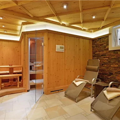 A relaxing sauna area with wooden paneling and loungers. Soft lighting creates a cozy atmosphere.
