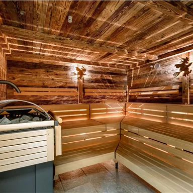 Eine moderne Sauna mit Holzverkleidung und sanfter Beleuchtung. Der Raum bietet entspannende Sitzbänke und eine angenehme Atmosphäre.