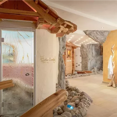 Ein luxuriöser Spa-Bereich mit natürlichen Steinelementen und einem entspannenden Ambiente. Die Wände sind in warmen Farben gehalten, und es gibt eine dekorative Wasserschale.