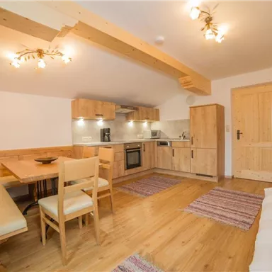 A bright, modern kitchen with wooden details and a cozy dining table. The space is friendly and inviting, ideal for relaxed meals.