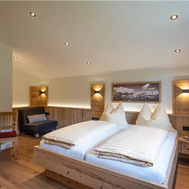 Ein gemütliches Schlafzimmer mit zwei Einzelbetten und warmen Holzmöbeln. Die Beleuchtung sorgt für eine einladende Atmosphäre.