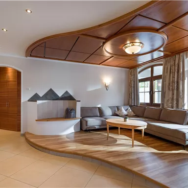 A modern living room with a wooden ceiling and large windows. The decor is cozy and inviting.