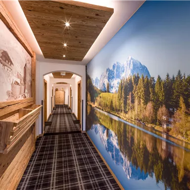 A redesigned hallway with a large mural of mountains and a lake. The floor is covered with a checked carpet, and the wooden decor adds a cozy atmosphere.