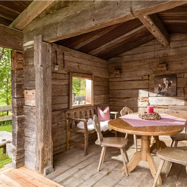 A cozy interior with a round table and wooden chairs. Light flows through the window and the atmosphere is rustic and inviting.
