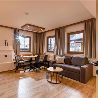 A modern living and dining room with bright windows and cozy furnishings. The wooden floor and stylish furniture create an inviting atmosphere.