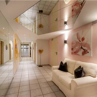A stylish hallway with a bright sofa and modern wall art. The walls and ceilings are designed with mirrors, which makes the space appear larger.