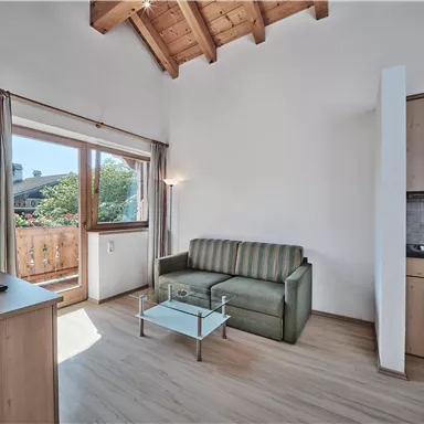 A bright living room with a sofa and a table. A beautiful view of nature is visible through the window.