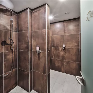 A modern bathroom with a shower and stylish tiles. The walls are in warm shades of brown and gray.