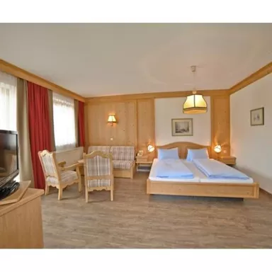 Ein gemütliches Hotelzimmer mit zwei Einzelbetten und einem Sitzbereich. Die Einrichtung ist hell und freundlich, mit Holzdetails und großen Fenstern.