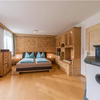 A cozy bedroom with wooden furniture and a double bed. The walls are made of wood and the atmosphere is warm and inviting.