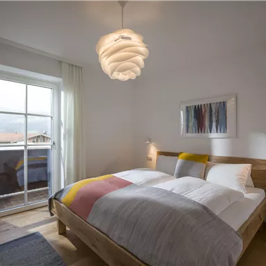 A cozy bedroom with a large window and a double bed. Modern design and soft colors create a relaxed atmosphere.