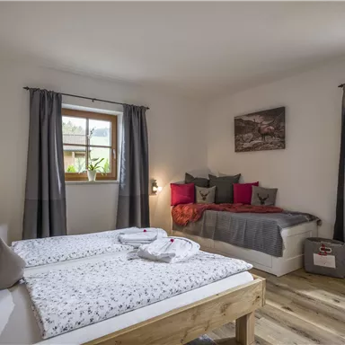 A cozy bedroom with two single beds and a daybed.  
Large windows provide plenty of daylight and a pleasant atmosphere.