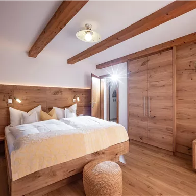 Ein gemütliches Schlafzimmer mit Holzdekor und einem großen Bett. Sanftes Licht und eine warme Atmosphäre schaffen eine einladende Umgebung.