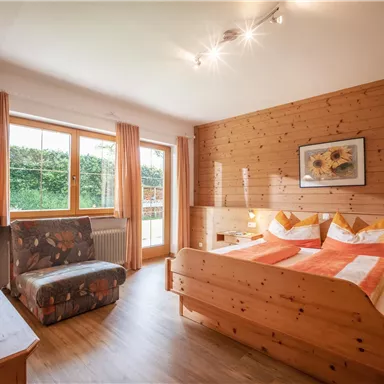 A cozy bedroom with wooden interiors. The room is bright and features a double bed and a television.