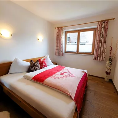 A cozy bedroom with a double bed and tasteful bedding. The room has a window with a view outside and an inviting atmosphere.